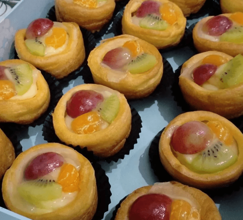 Soes buah dalam kemasan box dengan topping anggur, kiwi, dan jeruk mandarin